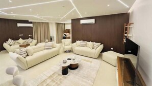A modern living room with a sectional sofa, a coffee table, and a flat-screen TV. - Lux privat hjem Sheikh zayed (Second Al Sheikh Zayed)