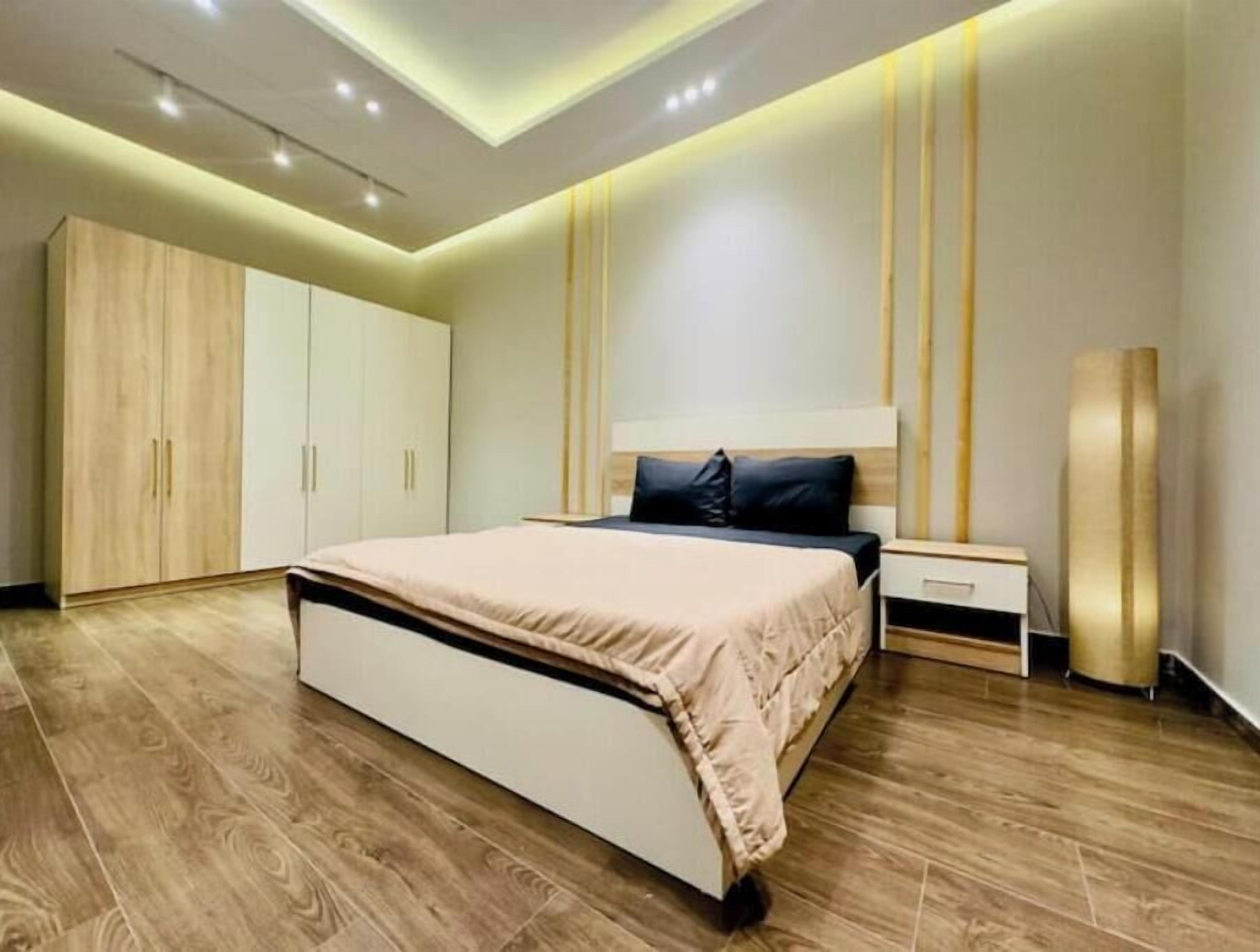 Ein modernes Schlafzimmer mit einem großen Bett, einem Holzschrank und einem Nachttisch.