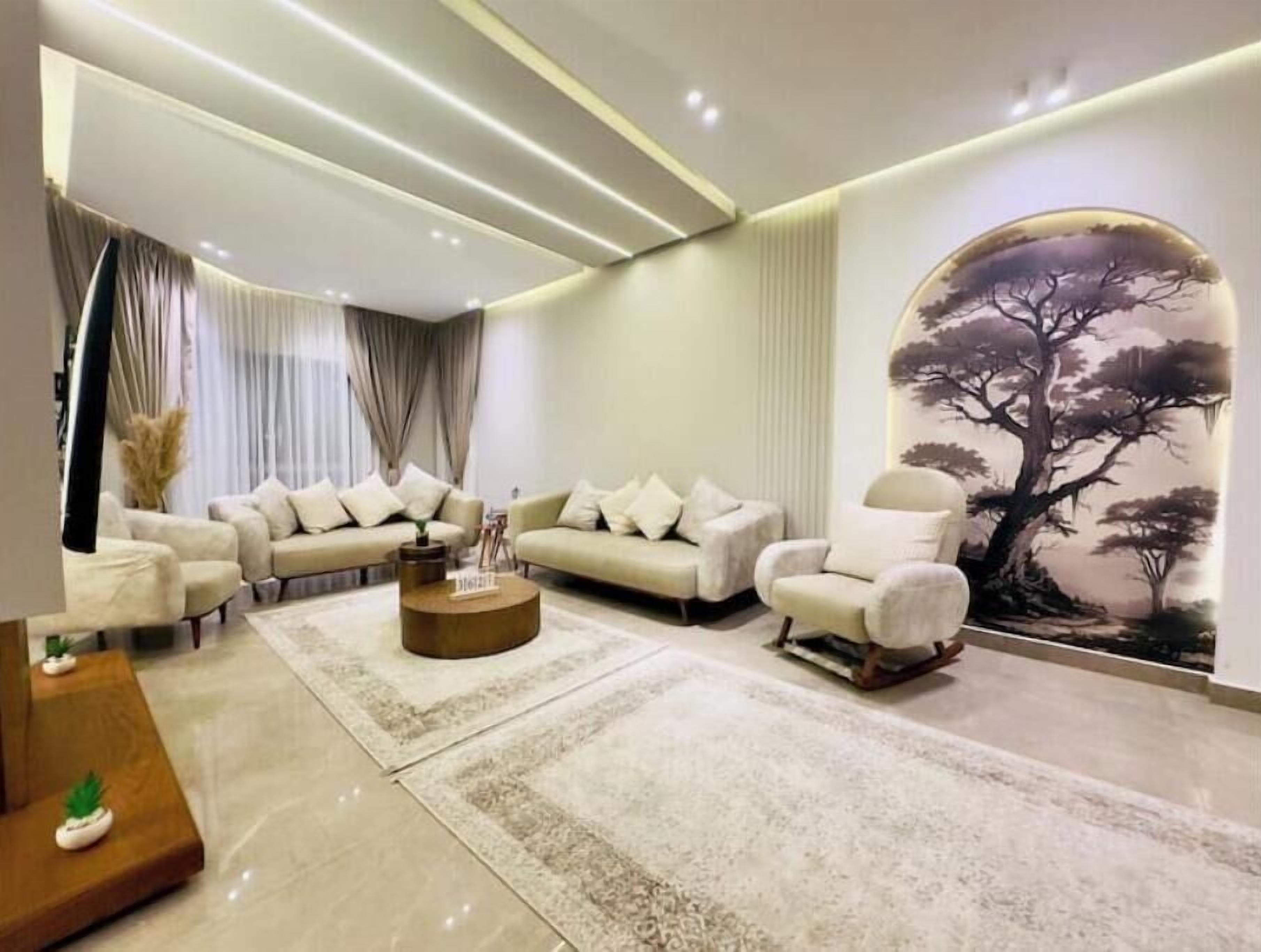 A modern living room with a sectional sofa, a coffee table, and a large wall mural.