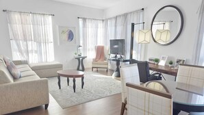 Una sala de estar moderna con un sofá, una mesa de centro, un televisor y un escritorio con una silla.