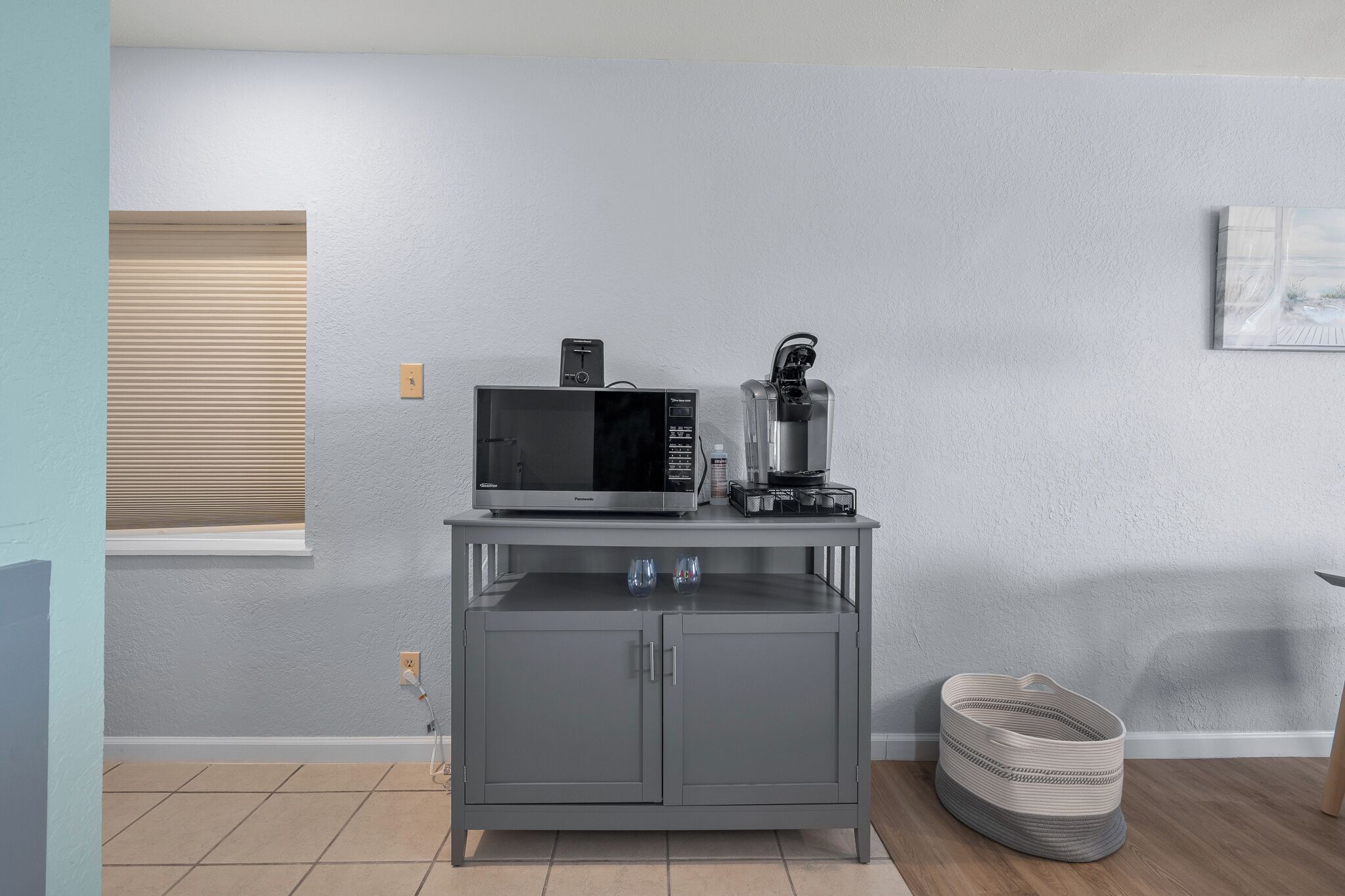 A compact kitchen with a microwave, coffee maker, and a small cabinet.
