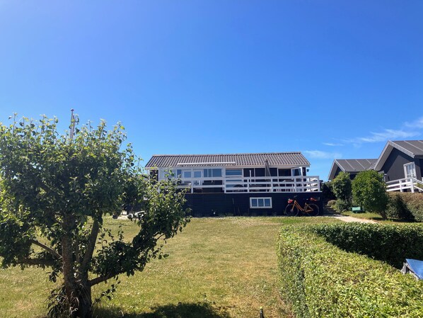 A two-story house with a balcony, surrounded by a well-maintained lawn and hedges.