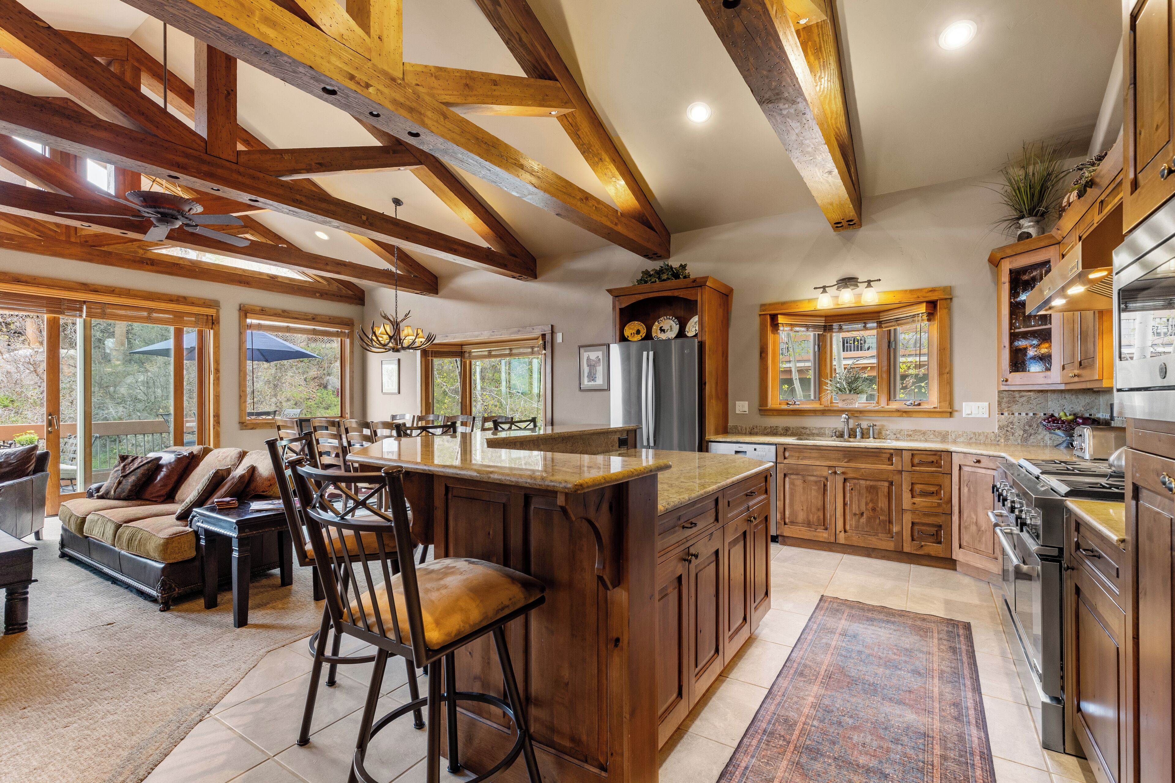 A spacious kitchen with wooden beams, a large island, and a bar area.