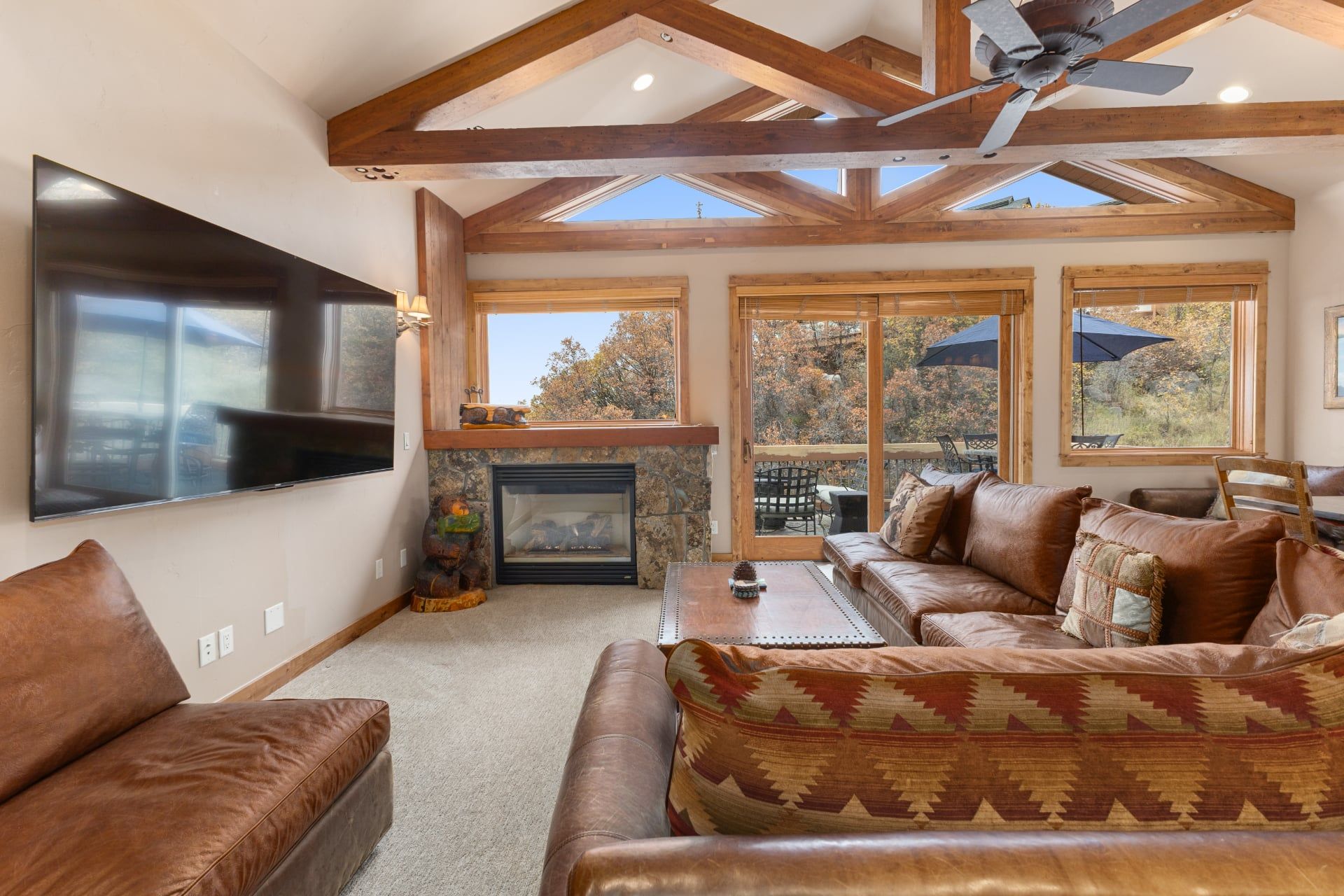 A spacious living room with a fireplace, leather sofas, and a large flat-screen TV.