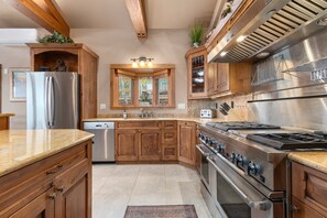 A kitchen with wooden cabinets, a stainless steel refrigerator, a built-in oven, and a gas stove.