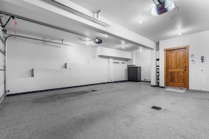 Ein geräumiger, gut beleuchteter Innenbereich mit Betonboden, einer Holztür und einem an der Decke befestigten Projektor.