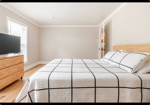 A bedroom with a large bed, a dresser, and a television on a stand. - Charming 3-bedroom house with AC in lovely Hammond (Hammond)