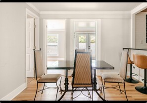 A dining area with a glass-top table, four chairs with patterned upholstery, and a wooden floor. - Charming 3-bedroom house with AC in lovely Hammond (Hammond)