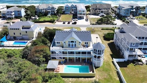 A coastal residential area with multiple houses, a large swimming pool, and a view of the ocean. - Semi-Oceanfront, Priv Pool, Hot Tub, ELEV, Rec Rm-WL980, OBX Beach Bliss (Corolla)