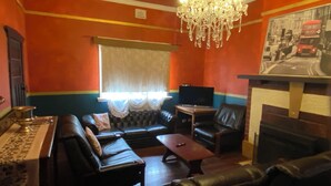 A living room with a sofa, a coffee table, a television, and a chandelier. - Pink Lakes Quairading (Quairading)