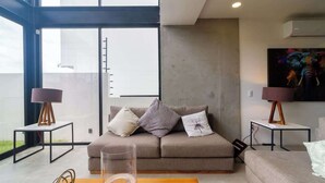 Ein modernes Wohnzimmer mit einer Couch, zwei Beistelltischen und einem großen Fenster.