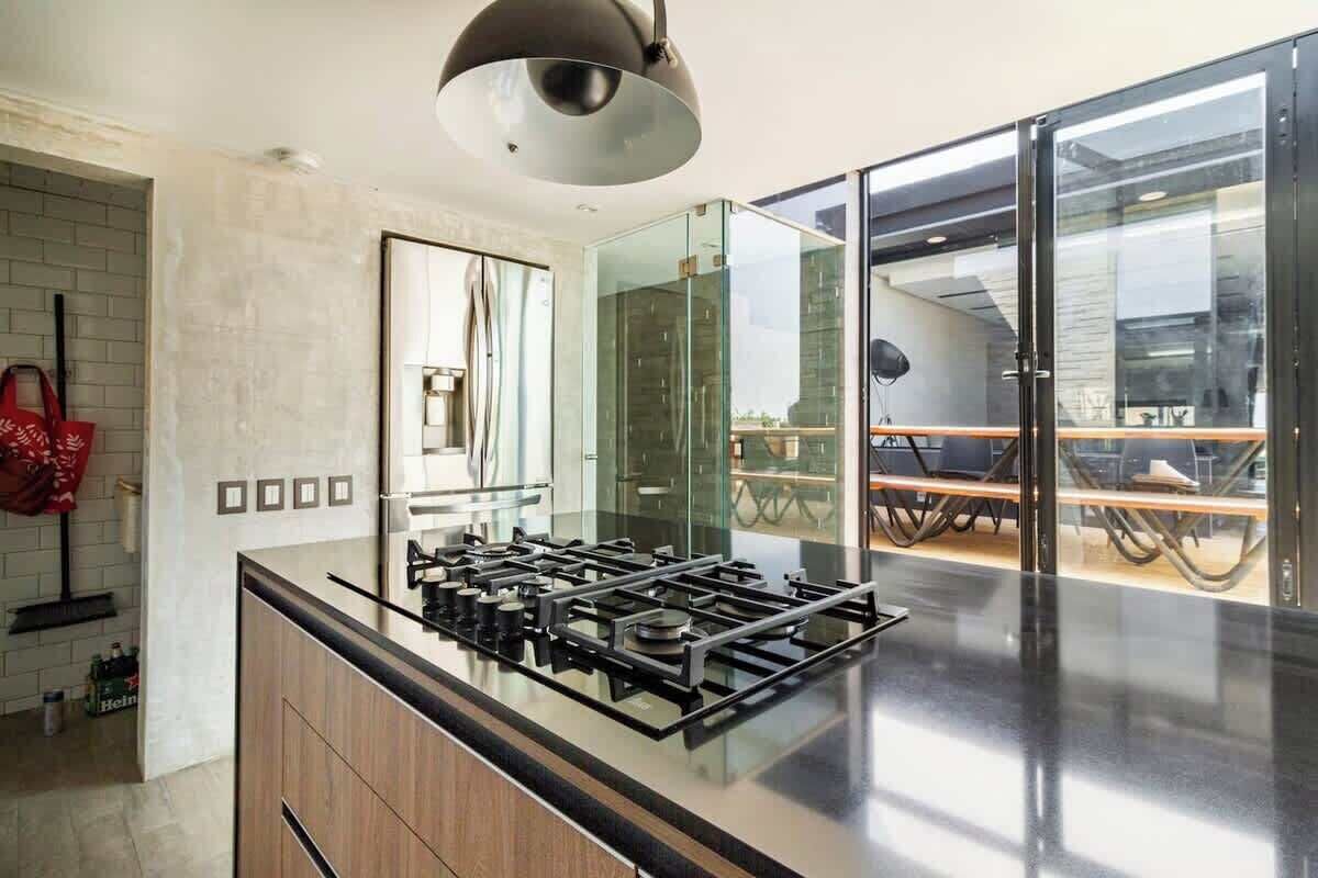 A modern kitchen with a gas stove, a large mirror, and a glass door leading to a dining area.