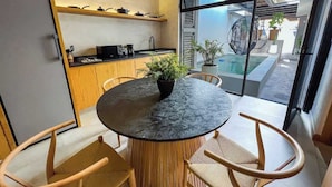 Een moderne keuken met een ronde eettafel, houten stoelen en een potplant.