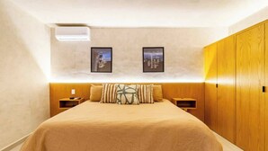 Een slaapkamer met een bed, twee nachtkastjes, een kledingkast en twee ingelijste foto’s aan de muur.