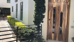 Un bâtiment moderne doté d’une porte en bois, d’un jardin vertical et d’un espace d’entrée pavé.