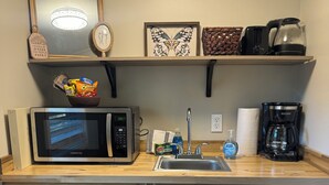 A compact kitchen with a microwave, toaster, coffee maker, and a small refrigerator. - Evergreen Escape 1 bed cabin near Tippy Dam, Trails, Lake Mi, Manistee River NEW (Wellston)
