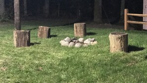 A stone circle surrounded by wooden stumps in a grassy area at night. - Evergreen Escape 1 bed cabin near Tippy Dam, Trails, Lake Mi, Manistee River NEW (Wellston)