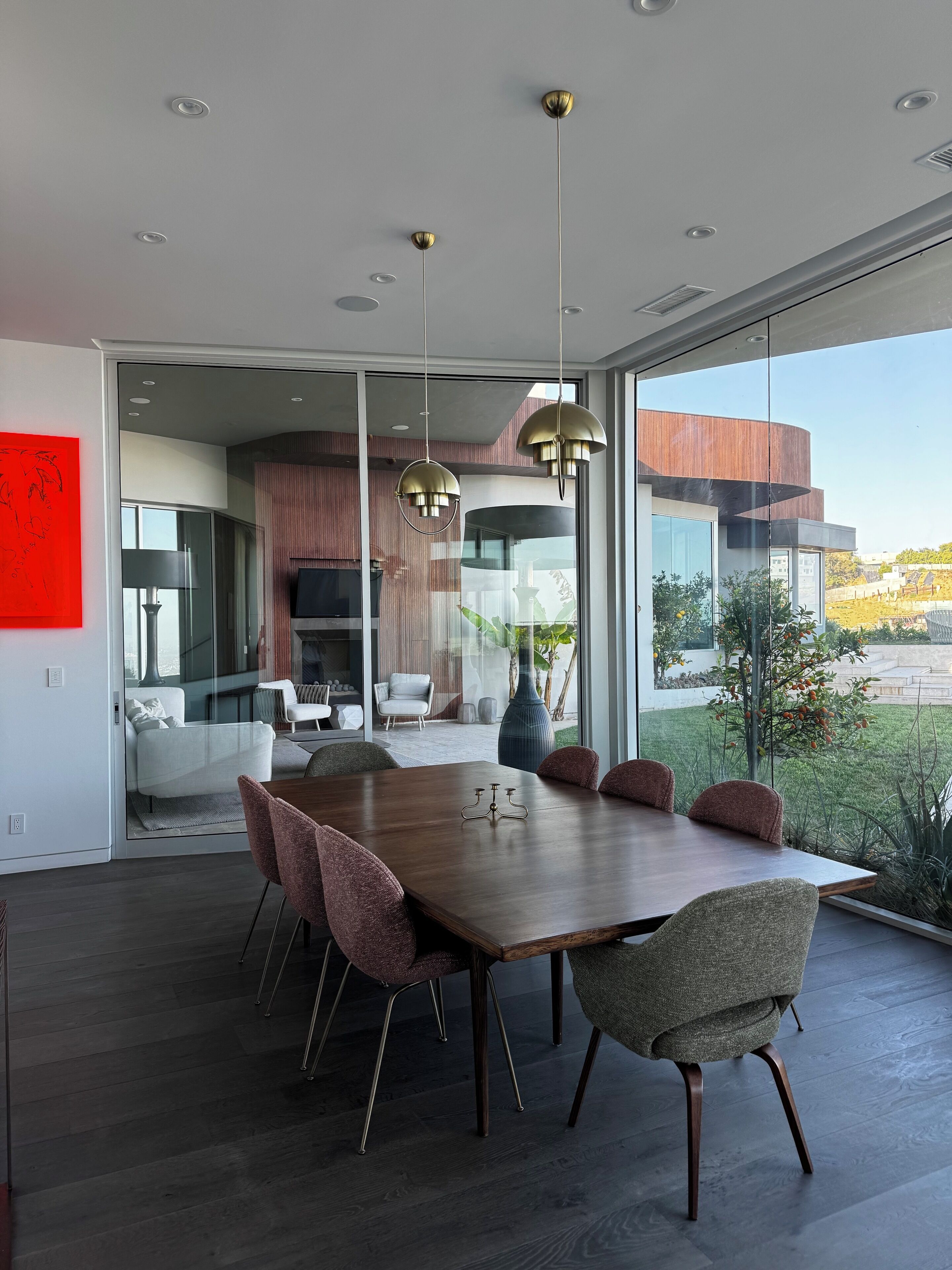 A modern dining area with a large wooden table, six chairs, and pendant lights.
