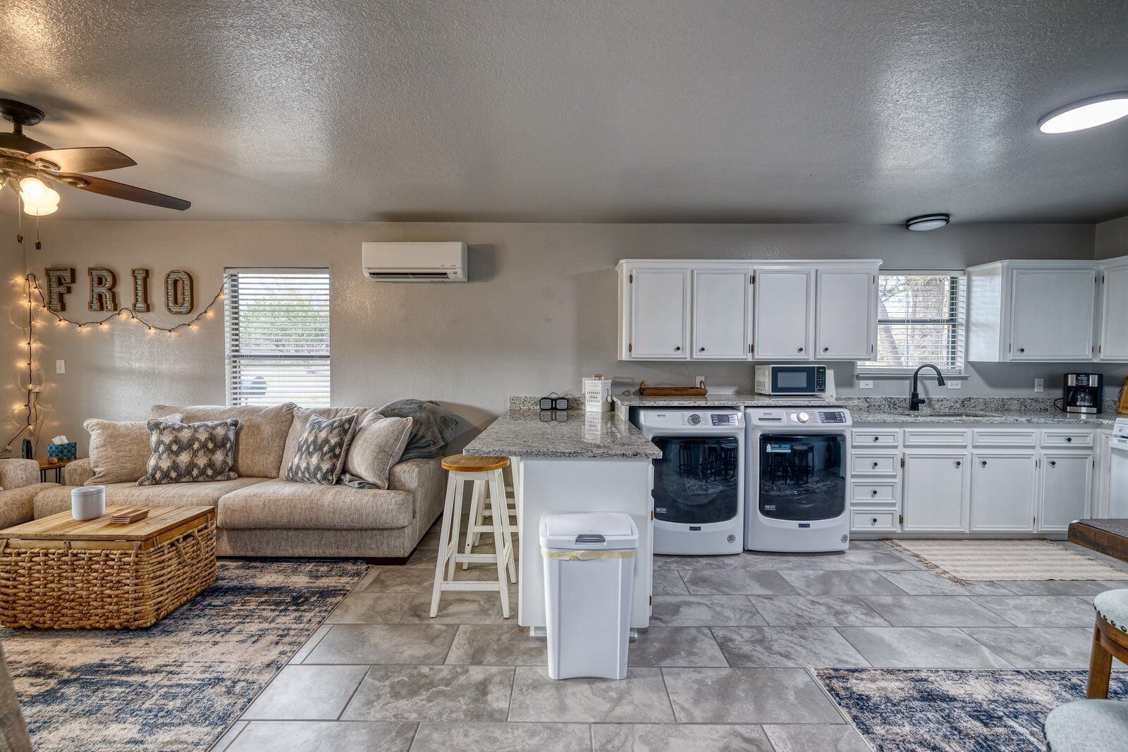 A modern kitchen with built-in appliances, a dining area with a wooden table, and a cozy living room with a sofa and decorative pillows.