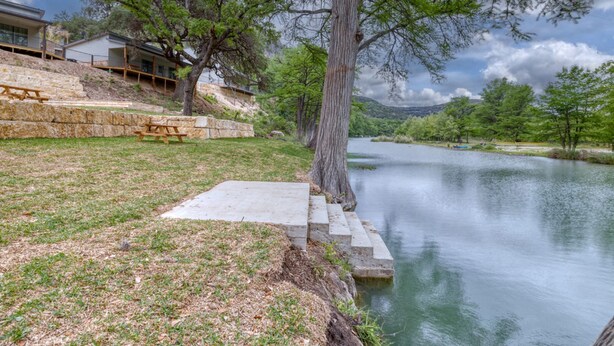 A riverside view with a picnic area and a stone staircase leading to a dock.