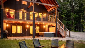 A two-story cabin with a fire pit and outdoor seating.