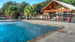 A swimming pool with a wooden deck and lounge chairs.