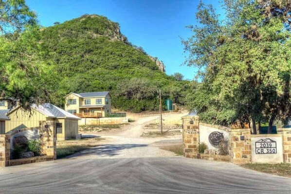 A residential area with houses, a dirt road, and a mountain in the background.