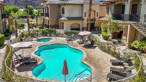 Un resort con una piscina centrale, diverse zone relax e uno sfondo montuoso.
