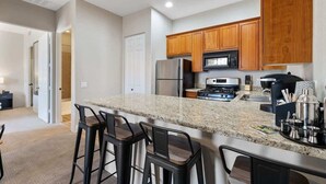 A modern kitchen with granite countertops, wooden cabinets, and stainless steel appliances. - Old Town La Quinta | Pool-View Terrace + Hot tub (La Quinta)