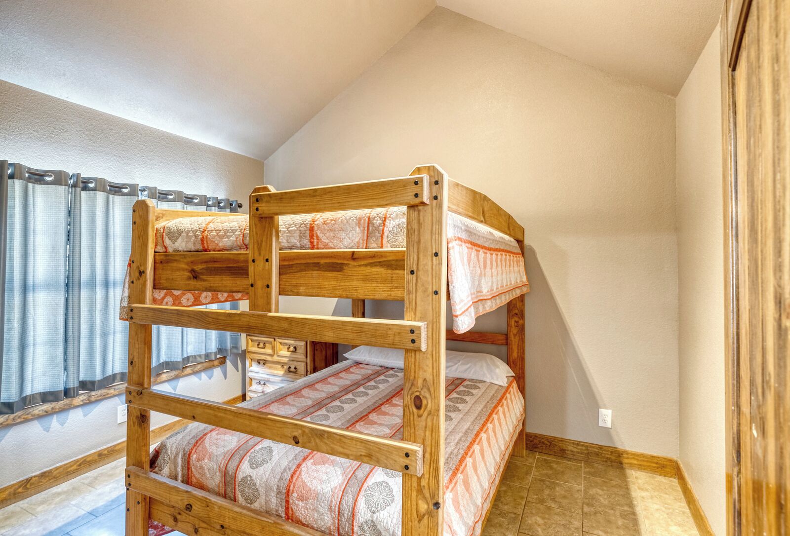 A bunk bed with two levels, wooden headboard, and patterned bedding.