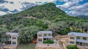 Una propiedad en una ladera con varias construcciones de piedra, cada una con una estructura de un piso y techo plano con ventanas amplias.