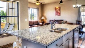 A kitchen with granite countertops, a sink, and a ceiling fan.