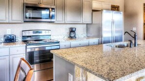 A kitchen with stainless steel appliances, granite countertops, and wooden cabinets.