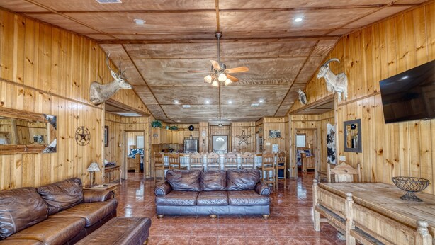 A wooden interior with a leather sofa, a dining area, and a TV.