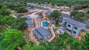 A residential area with houses, a swimming pool, and surrounding greenery. - River’s Edge Cabin #3 at Oasis Resort (Concan)