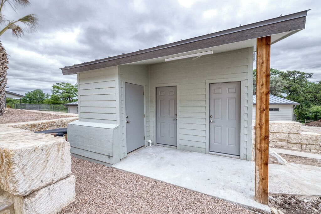 A single-story building with a covered porch, two doors, and a small concrete step leading to the entrance.