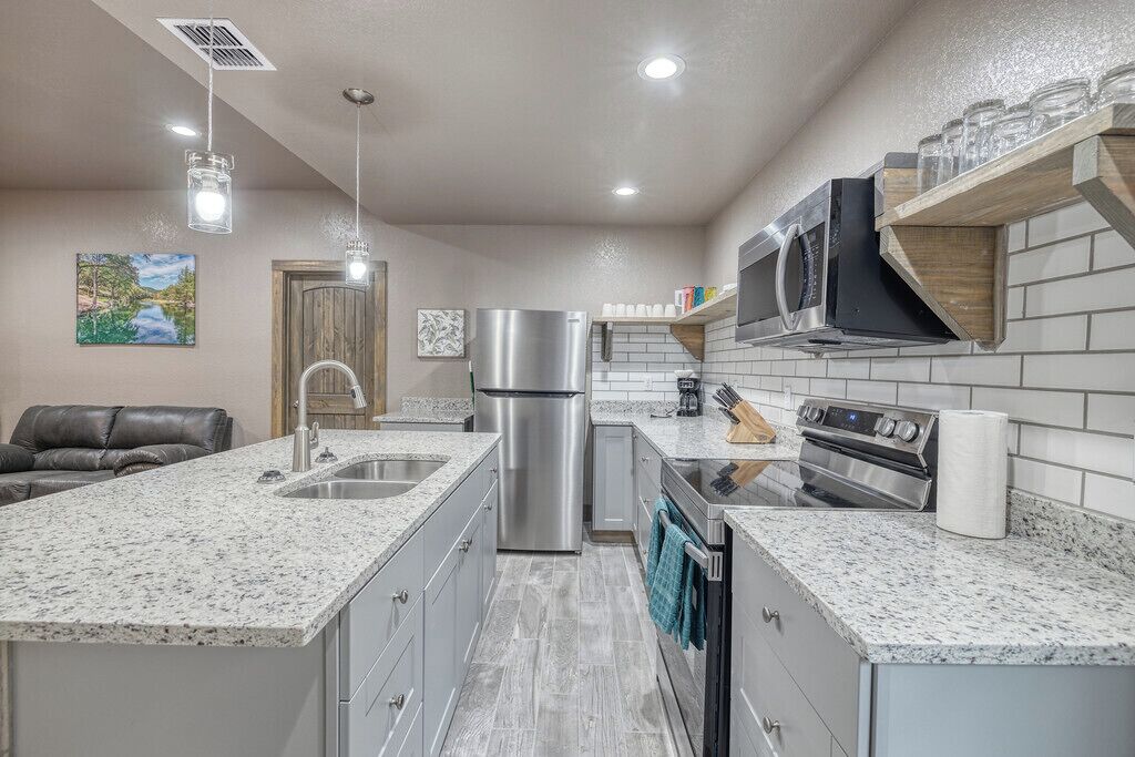 A modern kitchen with granite countertops, stainless steel appliances, and a built-in microwave.