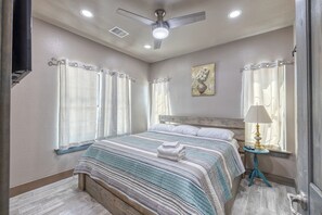 A bedroom with a bed, a nightstand, a lamp, and a painting on the wall. - Rivers Edge Home #1 on the Frio (Concan)