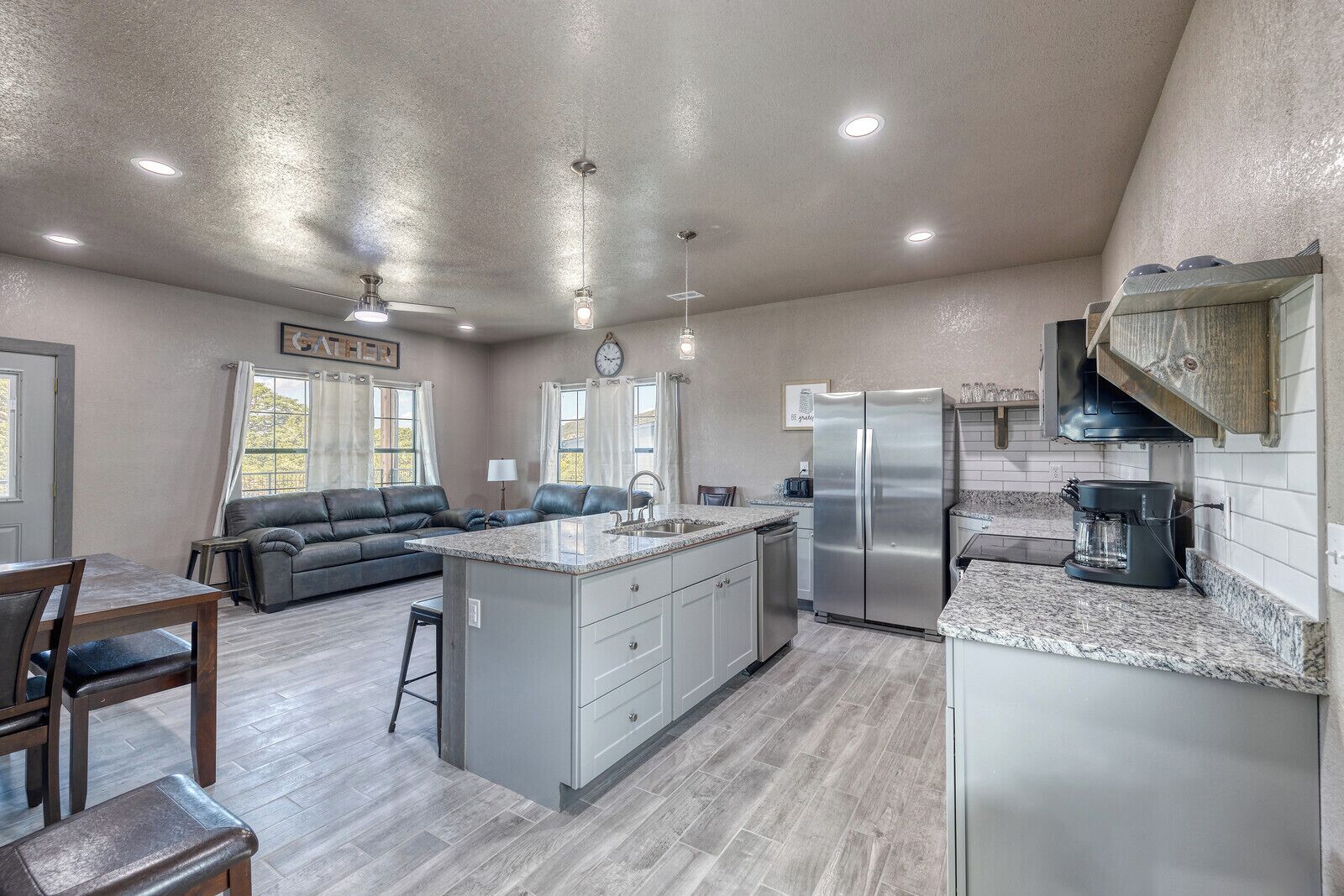 A spacious kitchen with a central island, stainless steel appliances, and a dining area with a sofa and chairs.