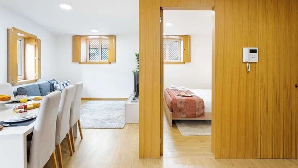 Een moderne kamer met een houten garderobe, een zithoek met een tafel en stoelen, en een bed met een rode deken.