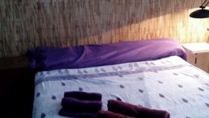 A bed with a patterned bedspread and two folded towels.