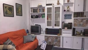 A living room with a red sofa, a television, and a bookshelf filled with books and decorative items.