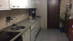 A compact kitchen with white cabinets, a stainless steel sink, and a black stove.