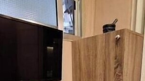 Un angolo cottura con forno a microonde, un piano di lavoro bianco e una finestra sopra il lavello.