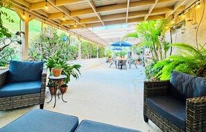 An outdoor patio with wicker furniture, potted plants, and string lights. - Walk to Lagoon/6 minutes from Legoland/Golfers Destination (Carlsbad)