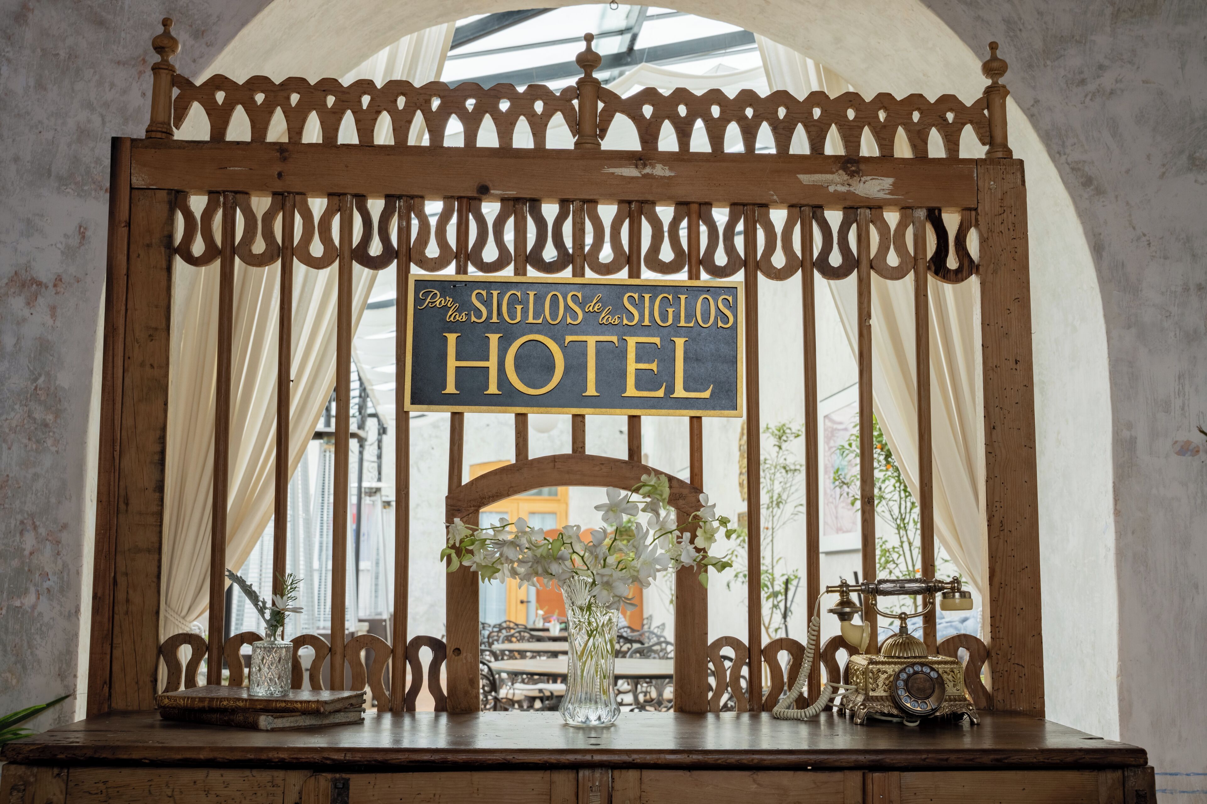 A wooden sign with the text 'Por los Siglos de los Siglos HOTEL' in a vintage style.