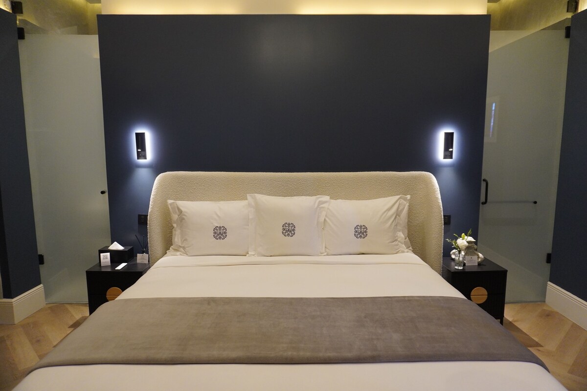 A modern bedroom with a large bed, two bedside tables, and a dark accent wall.
