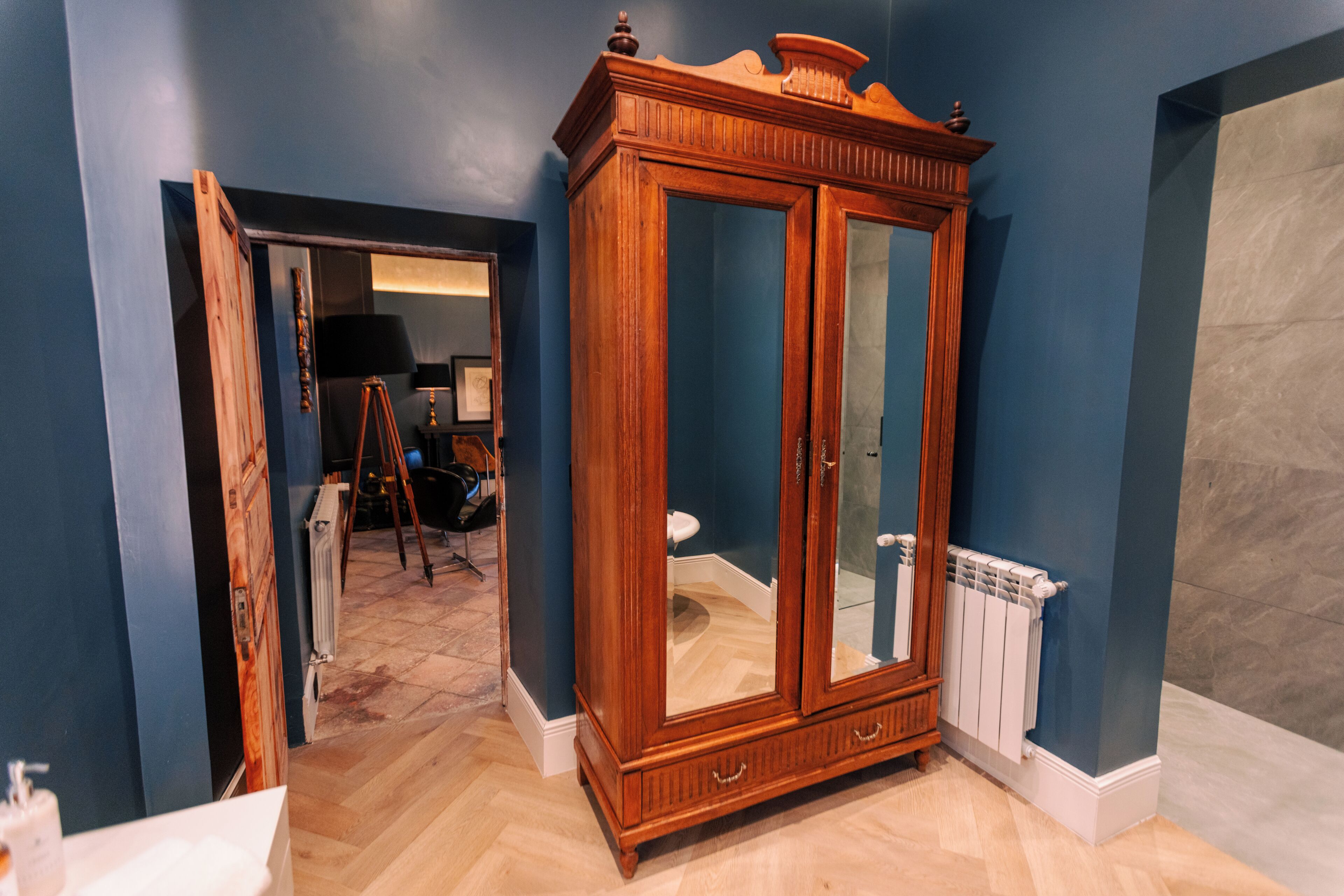Quarto com um armário de madeira grande, um radiador e padrão de piso em padrão herringbone.