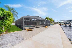 Un espacio al aire libre techado con piscina, un barco y un muelle.