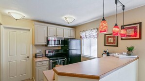 A modern kitchen with white cabinets, stainless steel appliances, and pendant lighting. - Coveted DTC Apartment! Free Parking & Fast WiFi! (Greenwood Village)